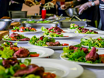 Freshly made meals on plates with meat and salad ready to be served to guests