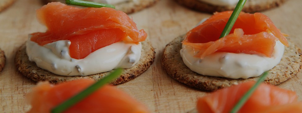 Close up of salmon and sauce on crackers for event catering