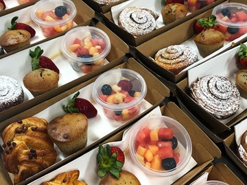 Close up of catering packs with fruit salad, pastry and muffin in each box