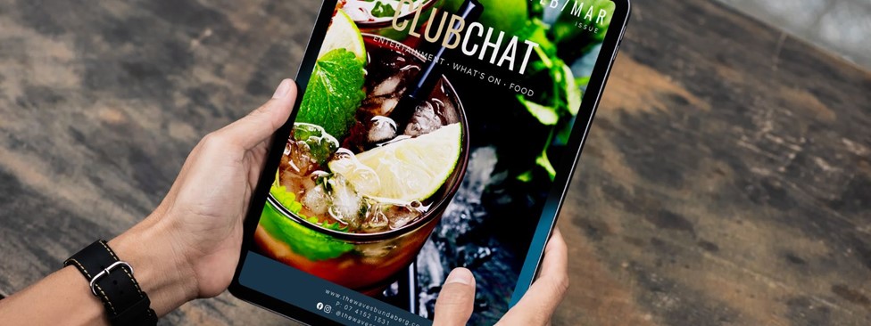Hands holding tablet device with ClubChat magazine on screen