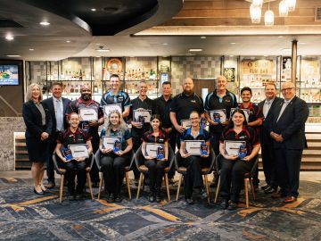 The Waves Bundaberg team holding awards in front of bar