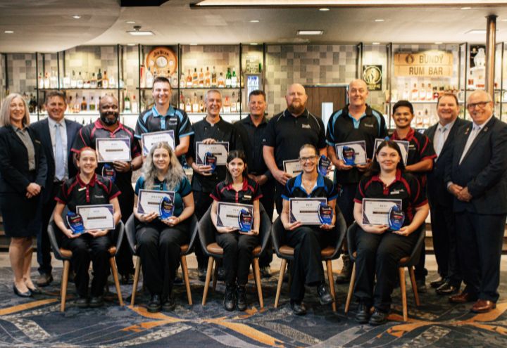 The Waves team stand together holding awards in front of bar
